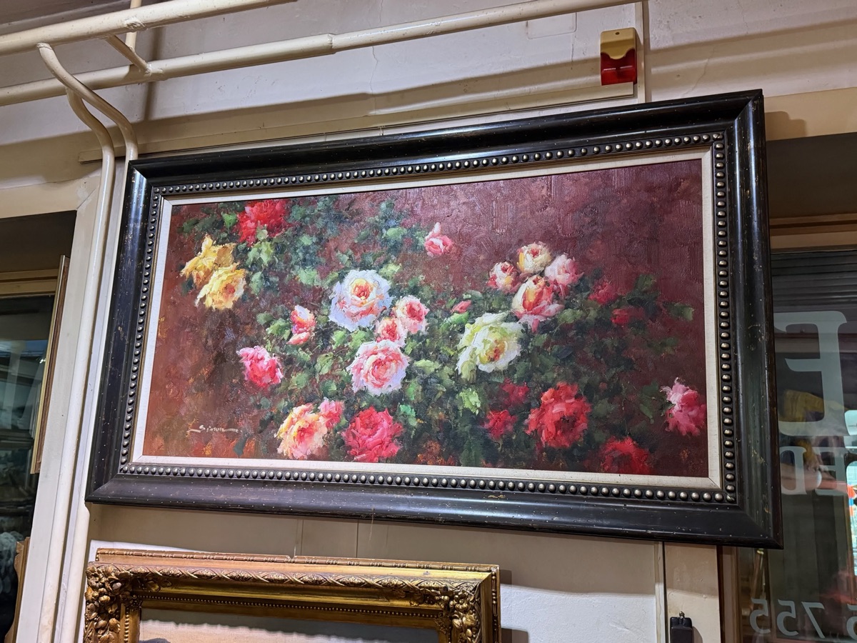 Gallery photograph of a framed painting of pink, white and yellow roses.
